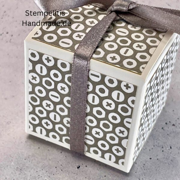handdekorierte Geschenkschachtel mit Aufschrift „Nur für dich“, Geschenkschachtel mit grauem Muster und rotem Etikett, kleine Geschenkbox mit Satinband, Vorderansicht der Schachtel „Nur für dich“, offene Geschenkbox mit Inhalt, Detailaufnahme Schriftzug „Nur für dich“, stilvolle Geschenkverpackung mit Band